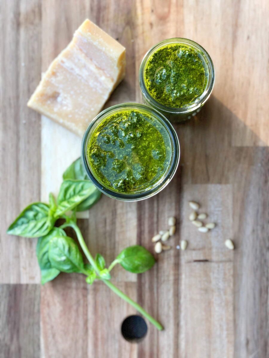 pesto maison dans 2 petits pots avec bloc de parmesan et feuilles de basilic