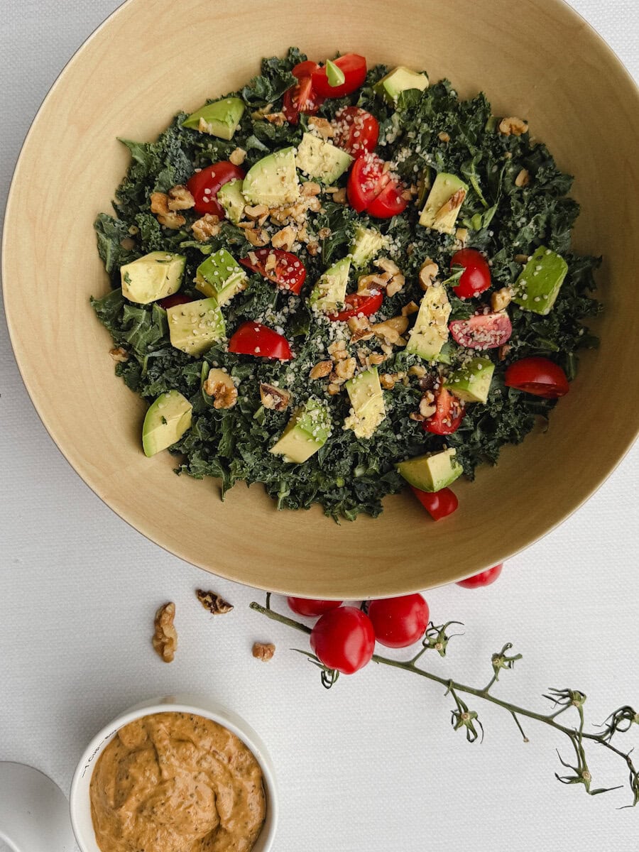 bol de salade de kale et tomates et avocat avec vinaigrette crémeuse sur comptoir blanc