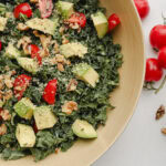 bol de salade de kale avocat et tomate avec tomates cerises à côté
