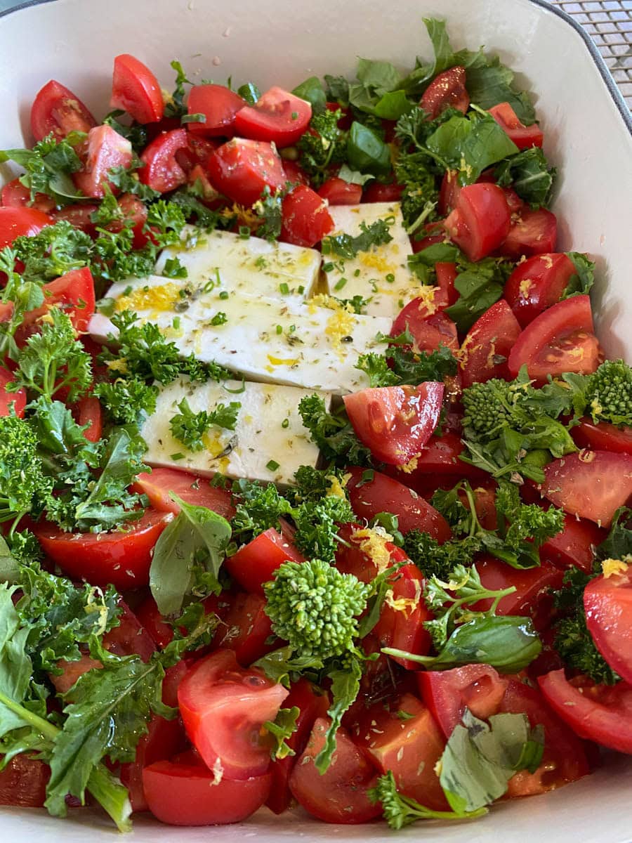 tomates en morceaux dans un plat avec morceau de fromage feta, herbes et huile (non cuit)