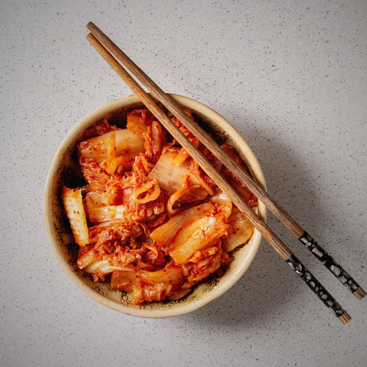kimchi maison dans un petit bol avec baguettes