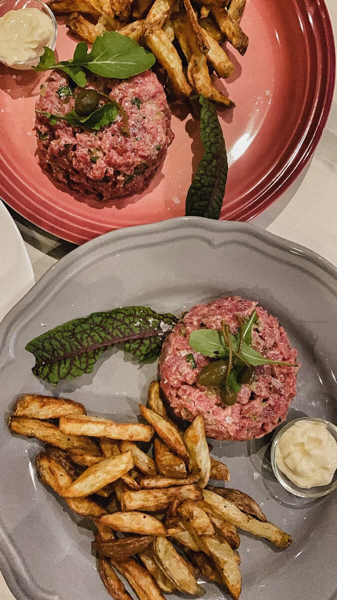 tartare de boeuf avec frites et cornichons dans deux assiettes lune rose un grise