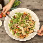 salade panzanella garnie de croûtons dans une assiette creuse blanche