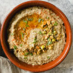 baba ganoush avec garniture de pistaches, huile d'olive et paprika dans petit plat en terre cuite