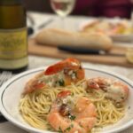 bol de spaghetti aux crevettes sur une table avec bouteille de vin en arriere plan