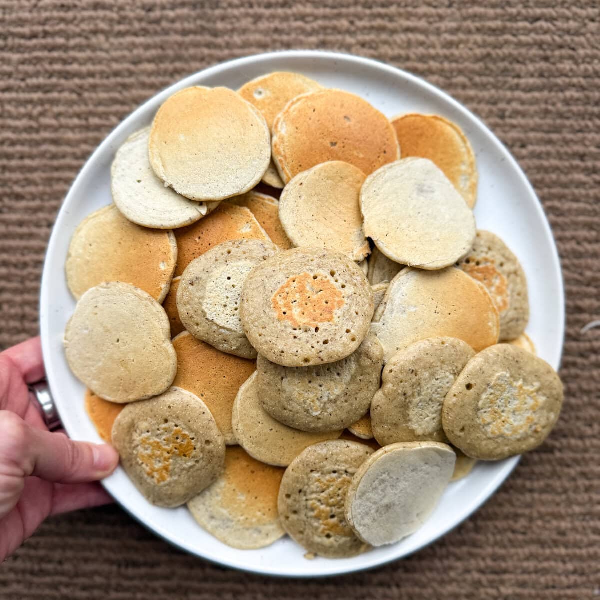 main tenant une assiette de blinis dorés