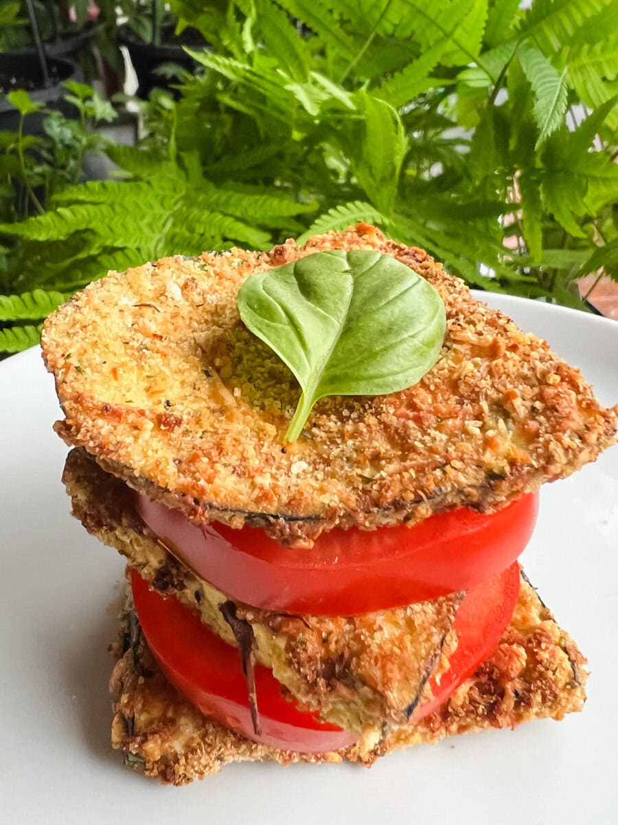 aubergine parmigiana air fryer, tranches d'aubergines panées entre tranches de tomates, garni d'une feuille de basilic