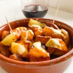 Patatas Bravas dans une petite casserole en terre cuite, avec sauce et cure-dents