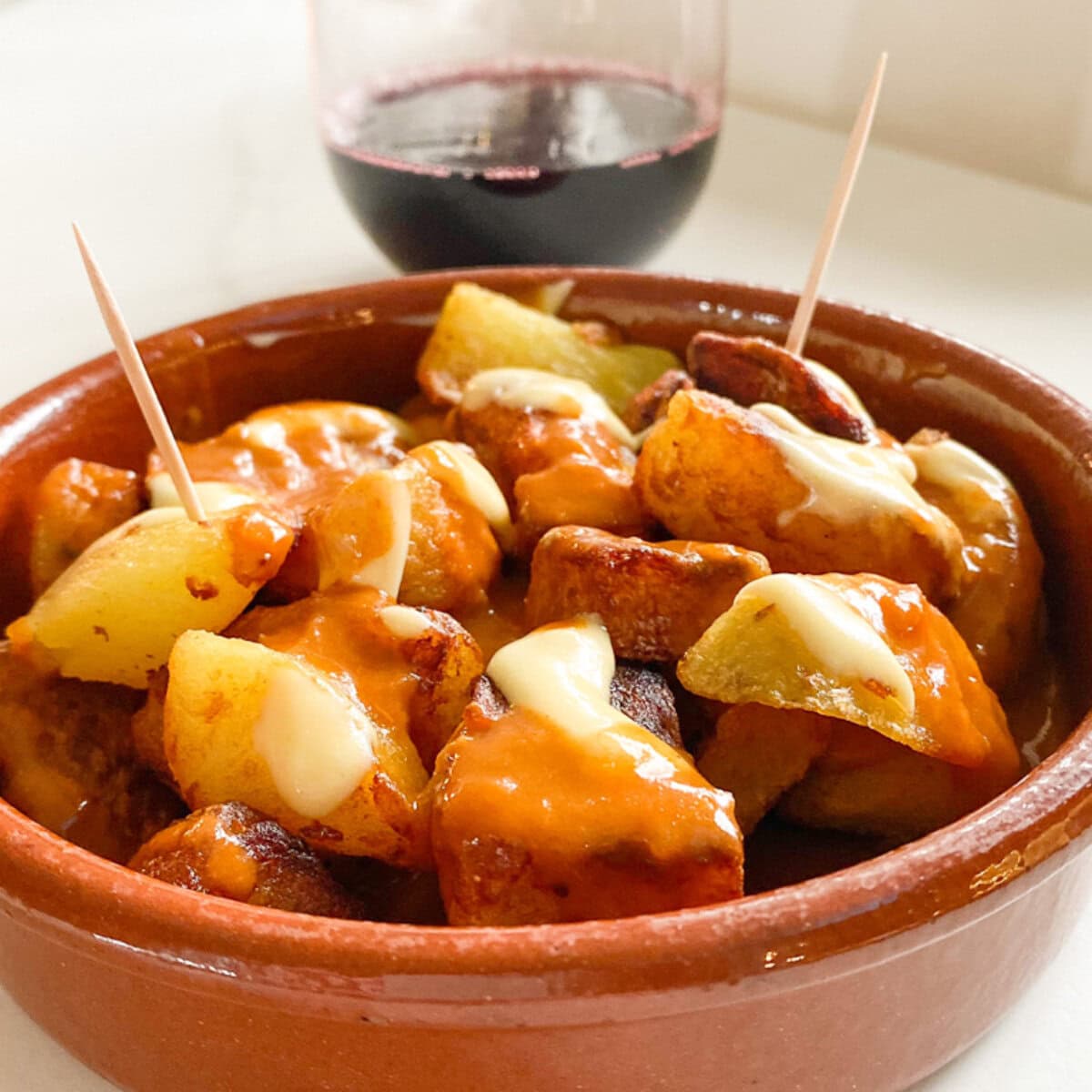 Patatas Bravas dans une petite casserole en terre cuite, avec sauce et cure-dents