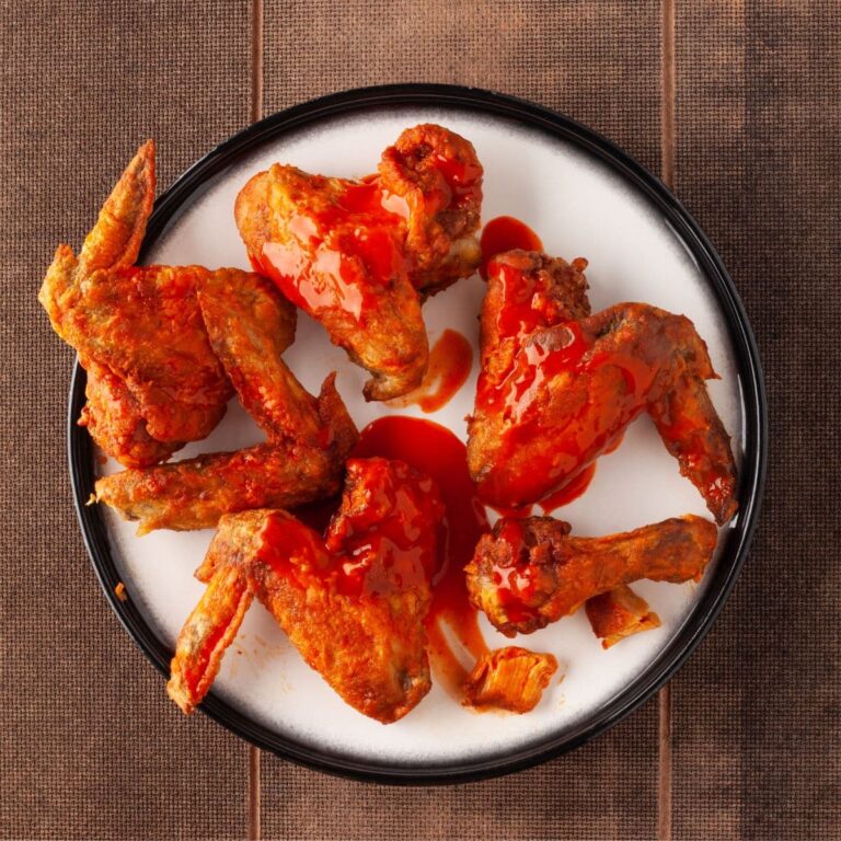 Ailes de poulet Buffalo air fryer sur assiette blanche contour noire avec sauce Buffalo