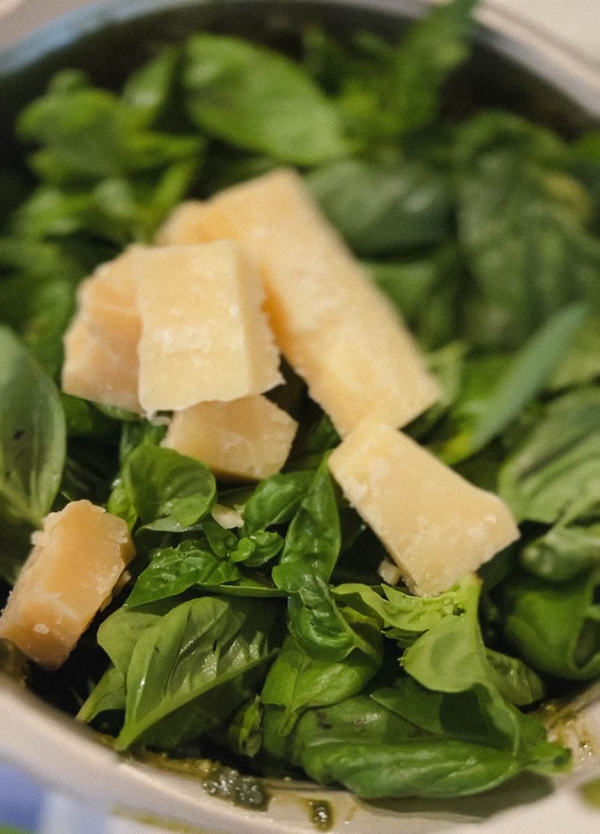 feuilles de basilic dans le bol du robot avec blocs de parmesan