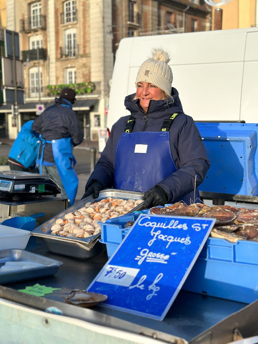 Vendeuse au marché de poisson avec Saint-Jacques fraiches