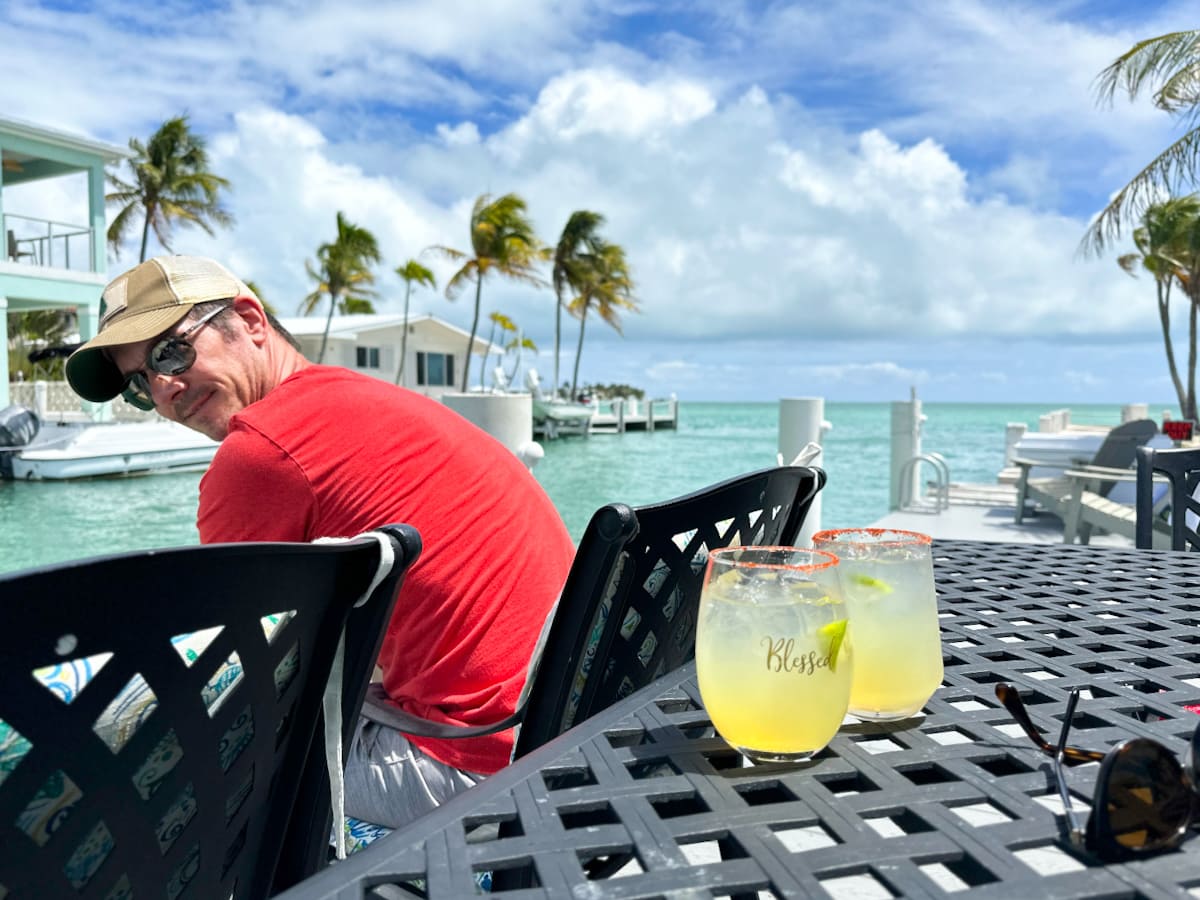 Lionel du Souich dans les Keys en Floride avec deux cocktails sur une table, vue sur la mer