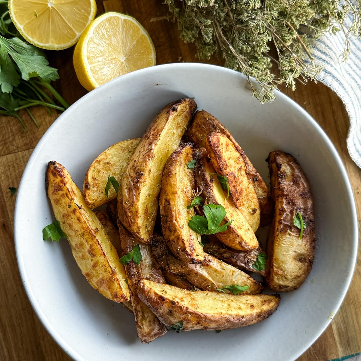 patates grecques air fryer dans un bol avec citron et origan sur une planche de bois