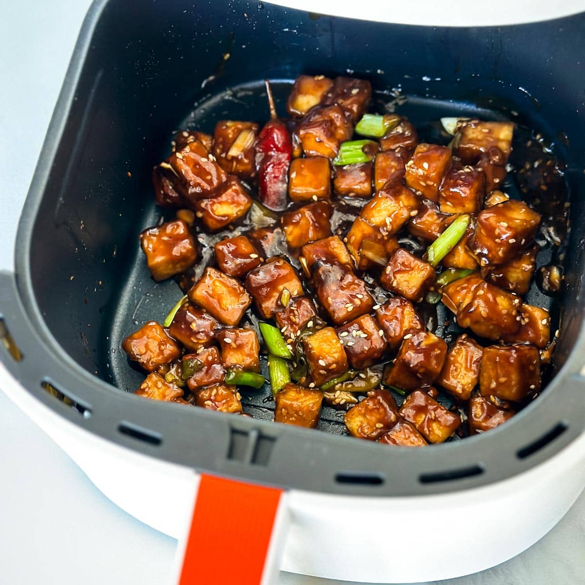 tofu Général Tao dans le panier du air fryer, bien grillé avec sauce