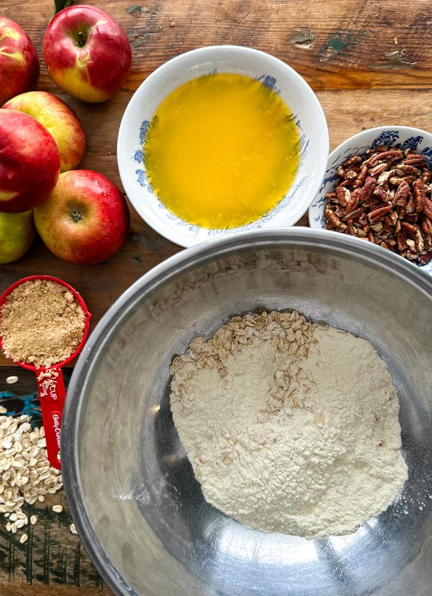 ingrédients pour croustade aux pommes sur la table: farine, avoine, beurre, pommes, cassonade, pacanes