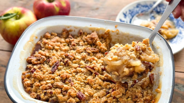 plat de croustade aux pommes, cuillère qui extrait une portion, pommes en arrière plan
