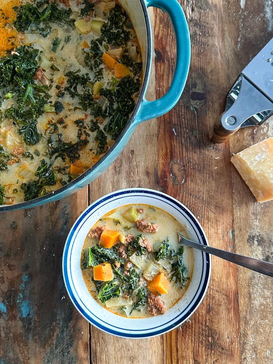 soupe toscane aux légumes, saucisse et fromage dans un bol sur une table avec casserole à soupe visible