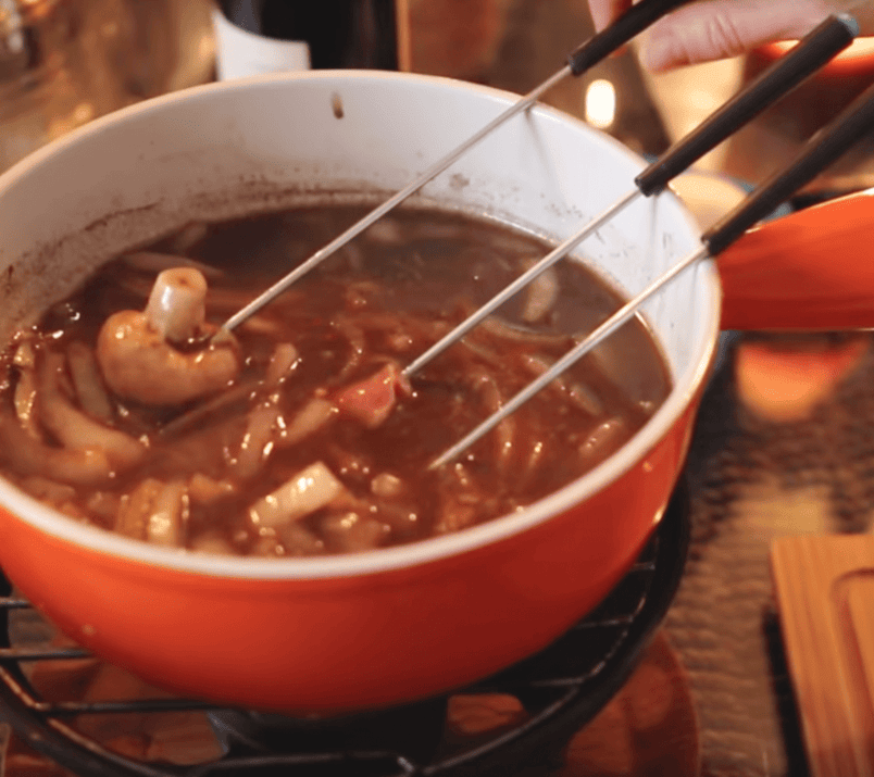 fondue chinoise dans un pot orange avec trois fourchettes