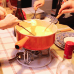 pot de fondue au fromage suisse avec des mains