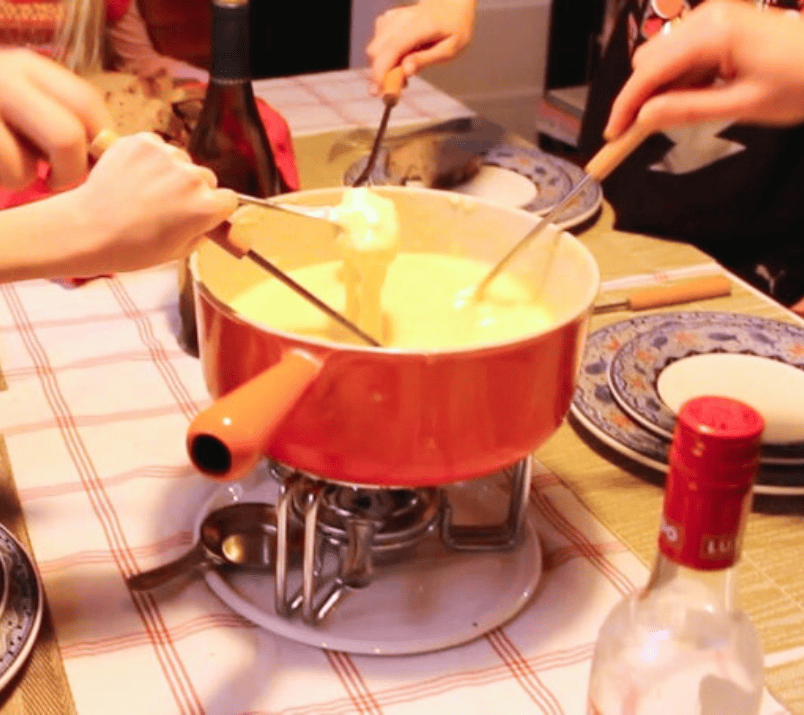 pot de fondue au fromage suisse avec des mains