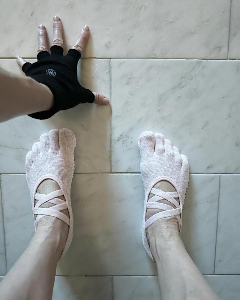 chaussettes de yoga  aux pieds et un gant anti dérapant sur plancher de marbre