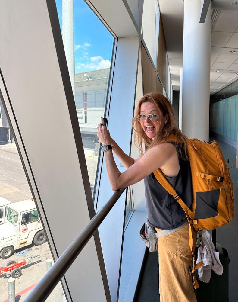 Manon Lapierre à l'aéroport sac à dos en train de prendre une photo avec son mobile
