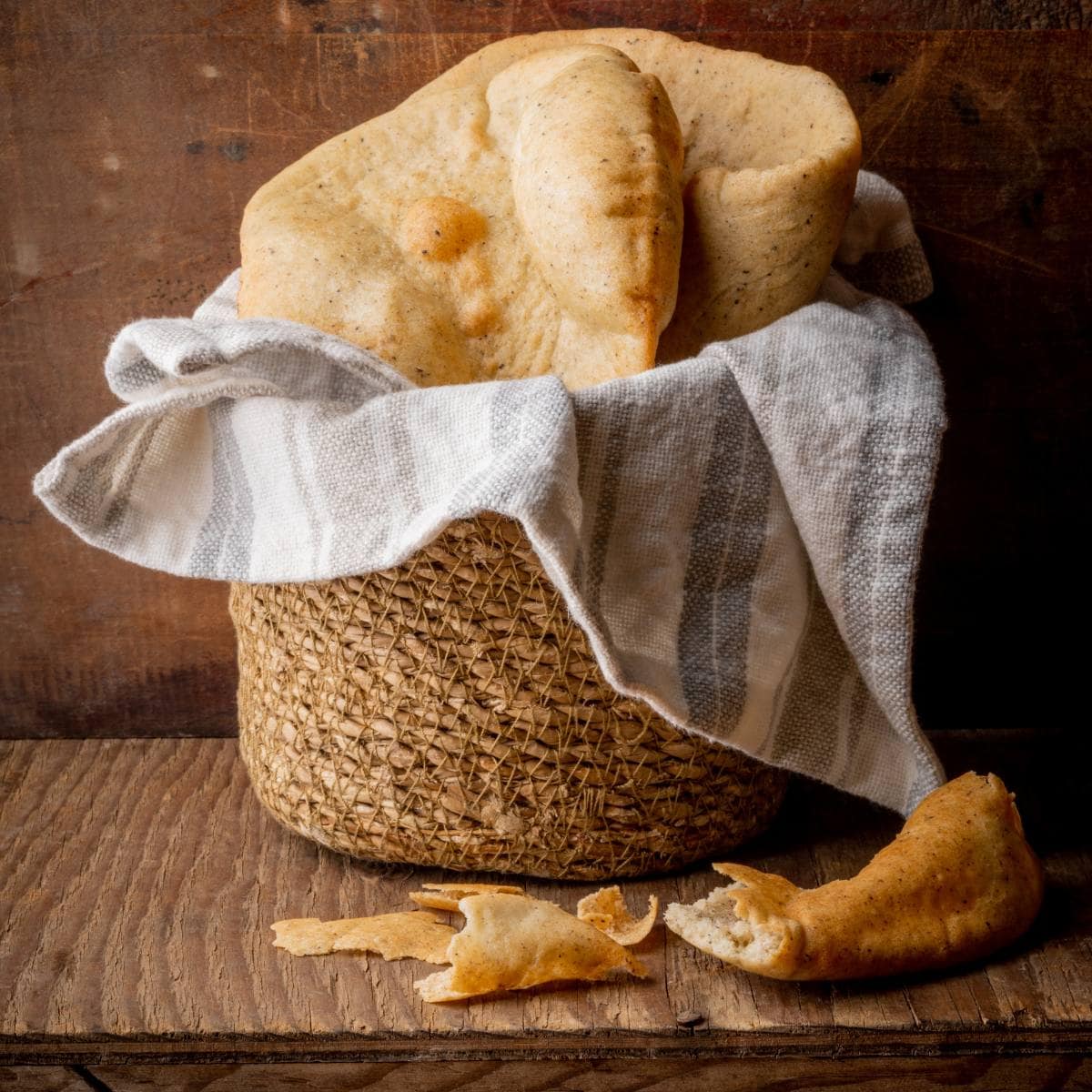 pains pita dans un panier avec un linge sur une table en bois
