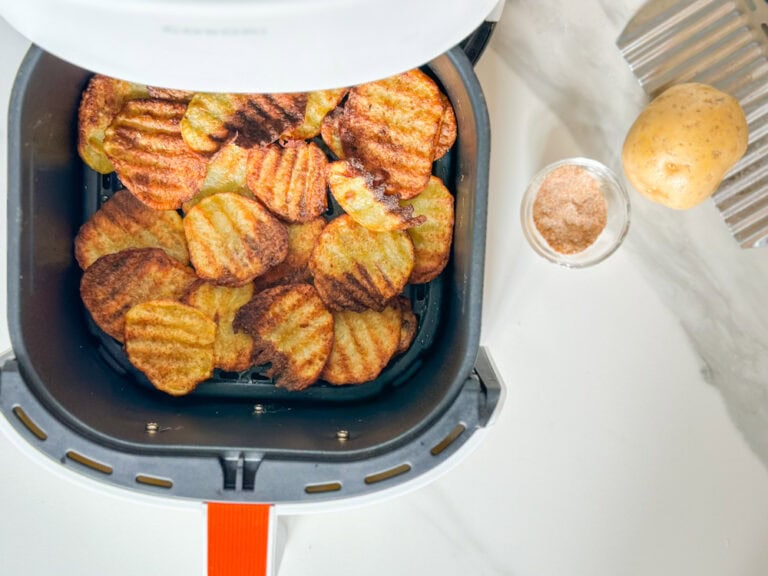 pommes de terre frites ondulées gaufrées grillées dans le panier du air fryer avec épices et pomme de terre sur le comptoir