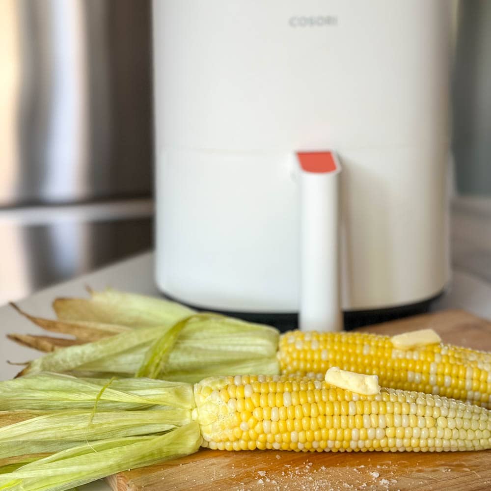 deux épis de maïs avec du beurre devant air fryer