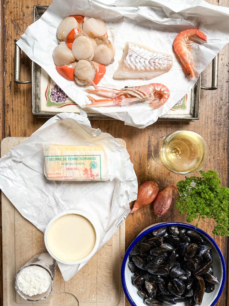 pétoncles (saint-jacques), poisson, crevette, langoustine, beurre, vin, crème, moules sur une planche de bois