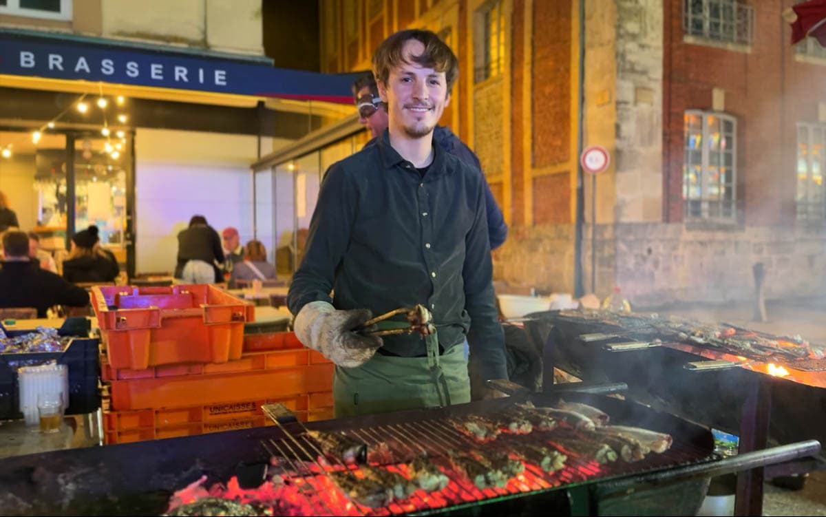 jeune homme devant grill avec harengs grillés, de soir