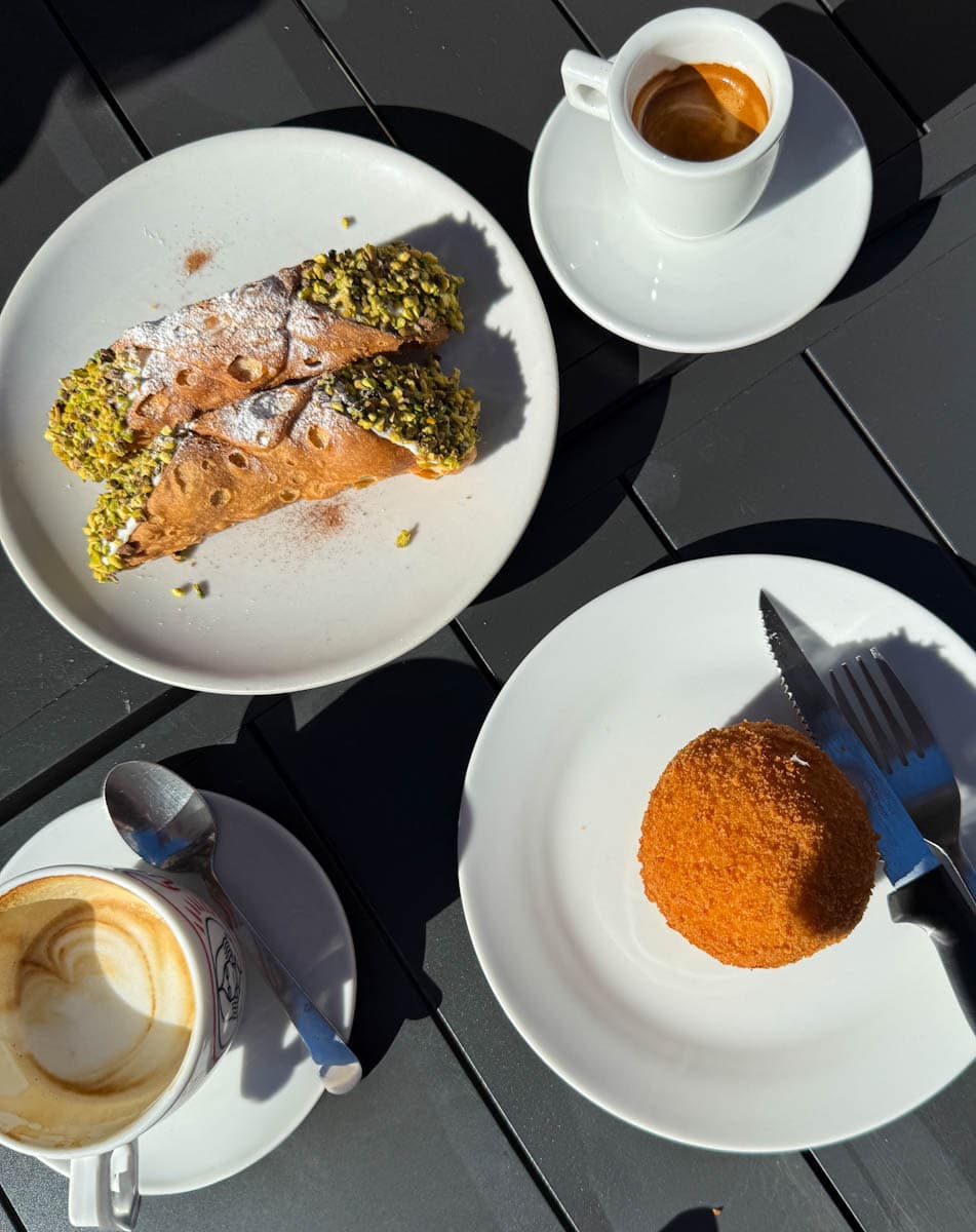 cafés, cannoli et arrancini dans un café sicilien sur une table noire