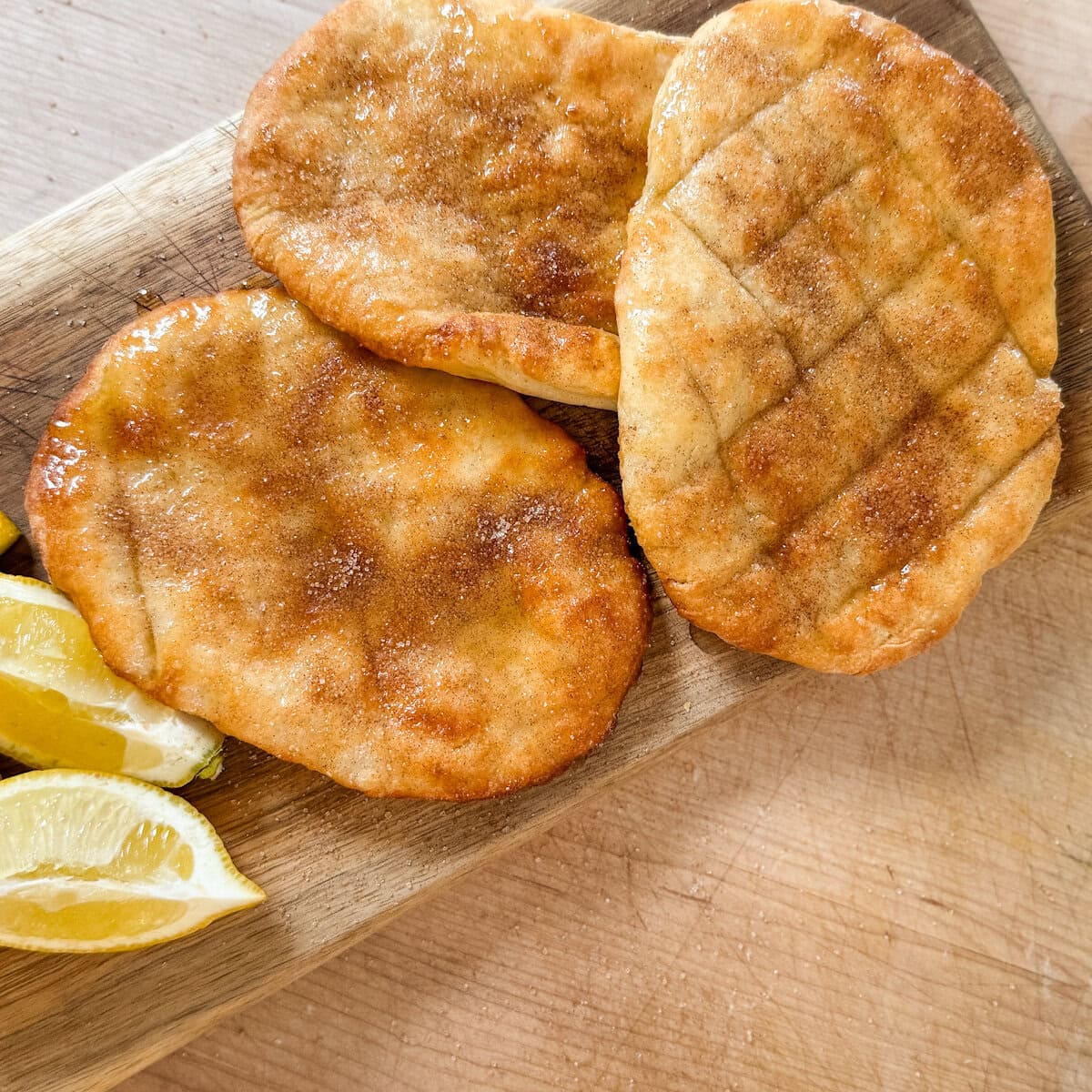 trois queues de castor (beignets) grillés et sucrés avec quartiers de citron sur planche de bois