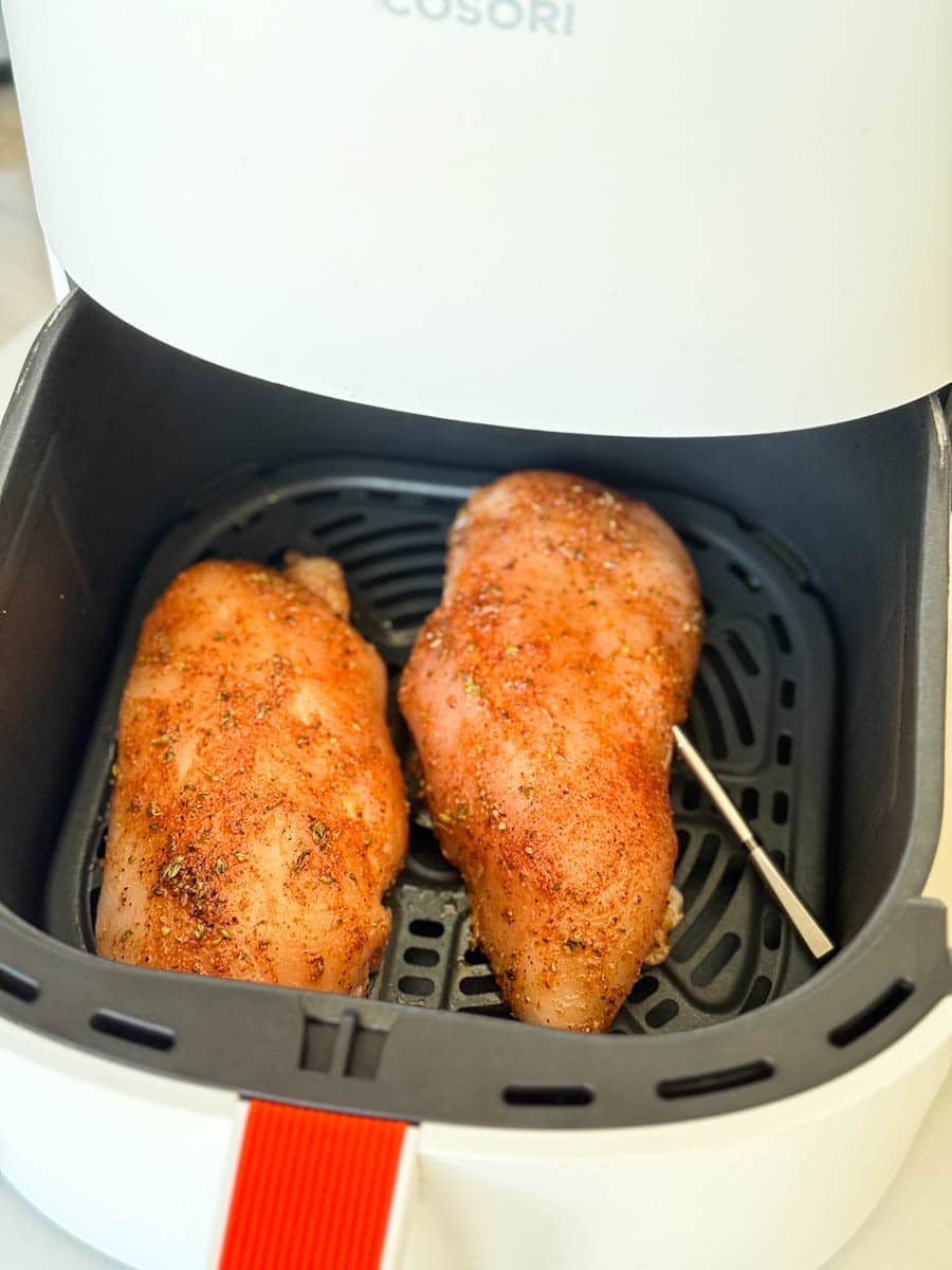 deux blancs de poulet assaisonné avec thermomètre dans le panier du air fryer