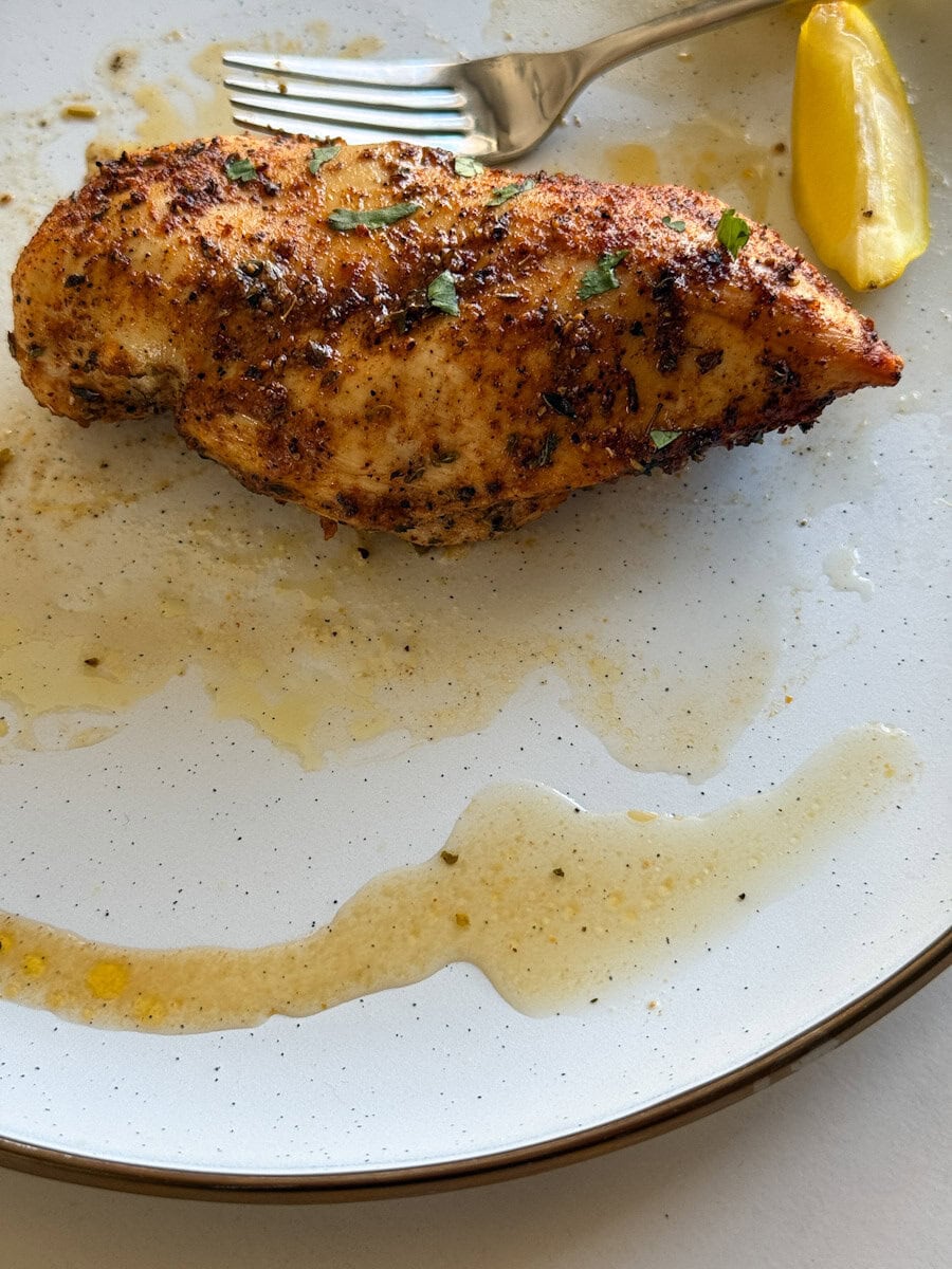 poitrine de poulet grillée et son jus dans une assiette blanche