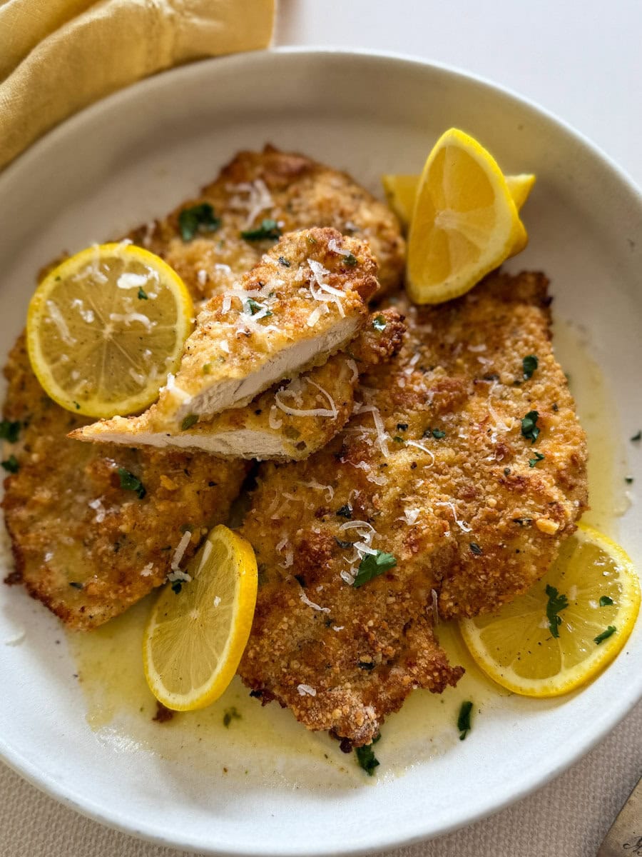 deux poitrines e poulet panées avec rondelles de citron et sauce citronnée dans une assiette blanche