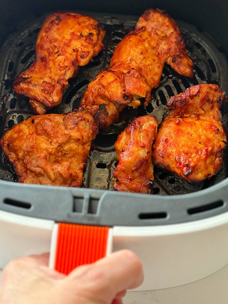 poulet gochujang dans le panier du air fryer tenu par une main