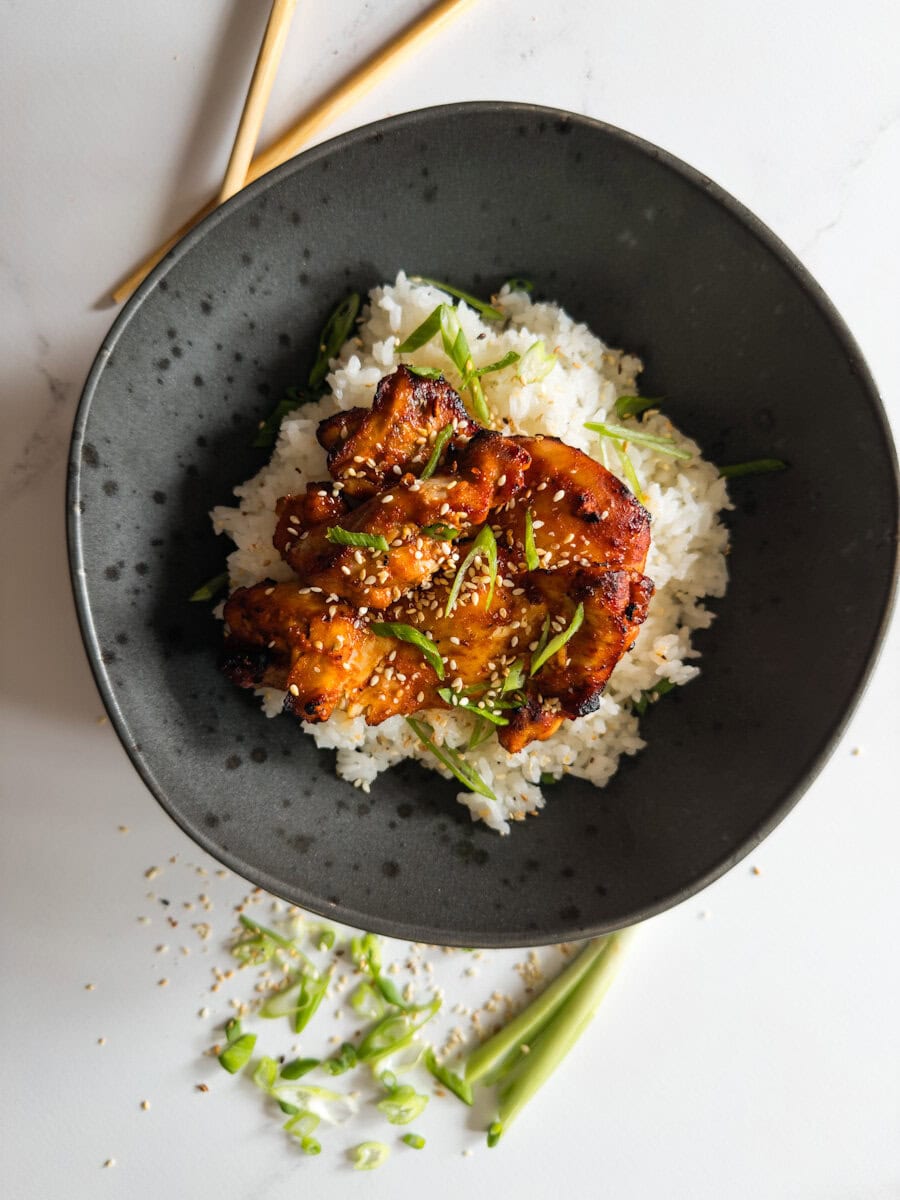 poulet gochujang air fryer dansun bol noir servi sur riz avec oignons verts