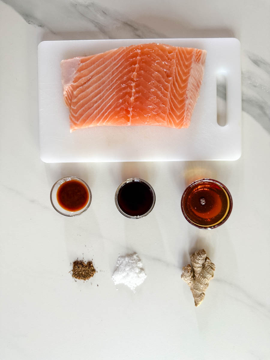 ingrédients sur comptoir: morceau de filet de saumon, petits pots de sauce tamari, sirop d'érable, sauce chipotle, fleur de sel, gingembre et poivre