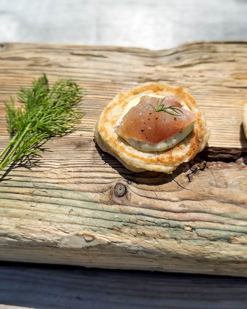blinis avec gravlax sur planche de bois avec tiges d"aneth