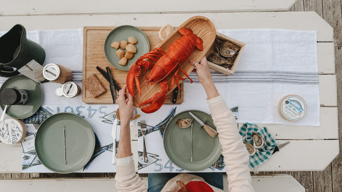 pique-nique des Îles de la Madeleine, table blanche en bois, homard, pétoncles, fromage, pâté, etc