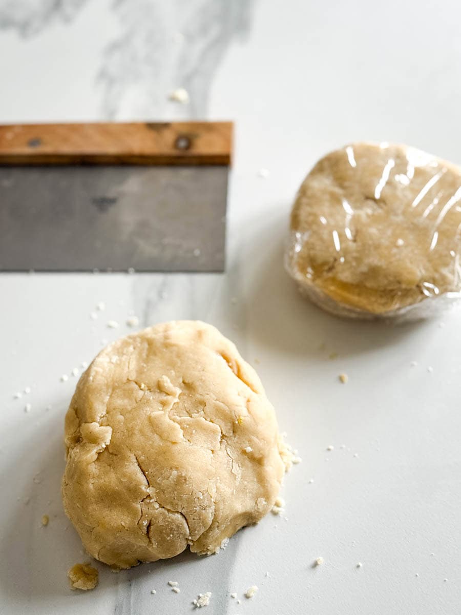 boule de pâte emballé dans film alimentaire et une déballée avec coupe pâte sur comptoir
