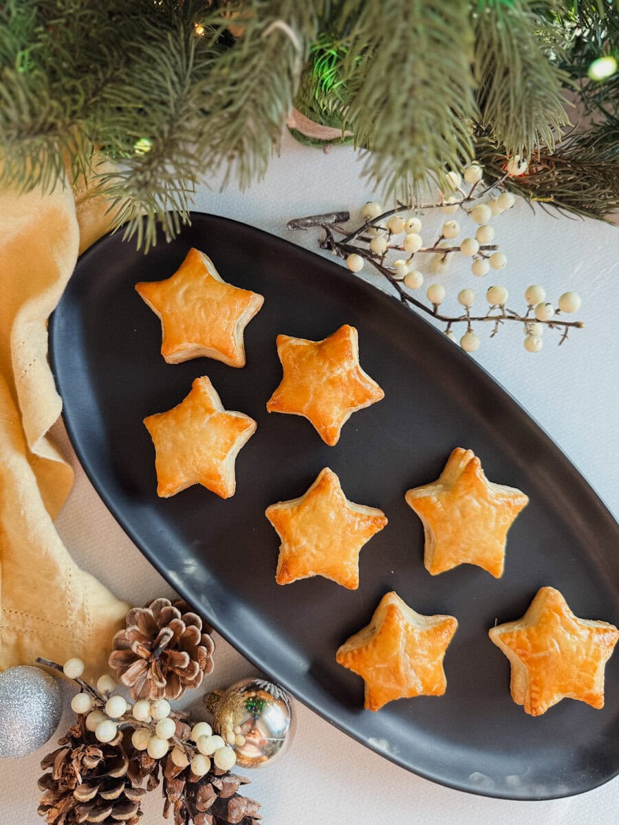 feuilletés festifs apéro en forme d'étoile dans une assiette ovale avec décorations de Noël