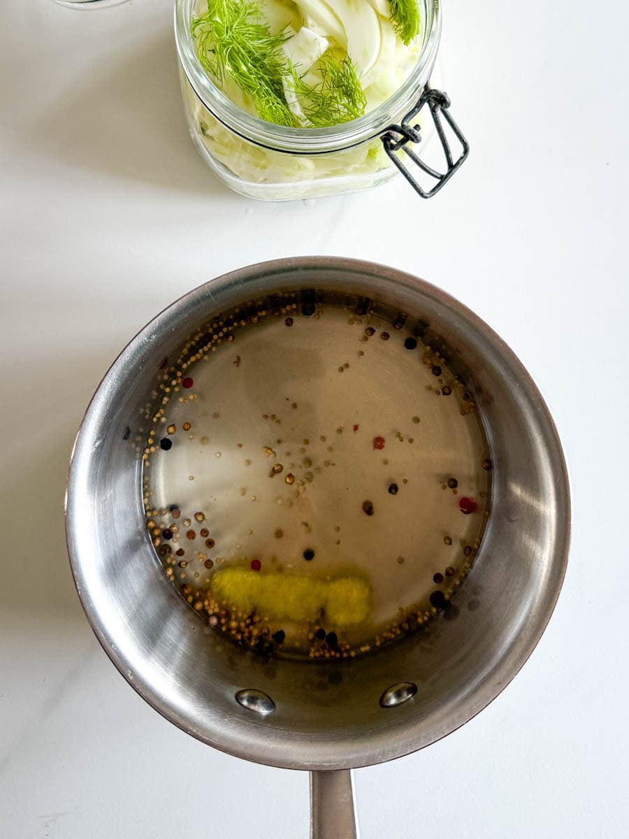 liquide à marinade dans petites casserole en stainless à côté de pot à marinade