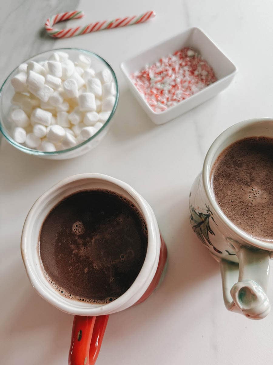 2 tasses de chocolat chaud avec bol de guimauve et canne de Noël