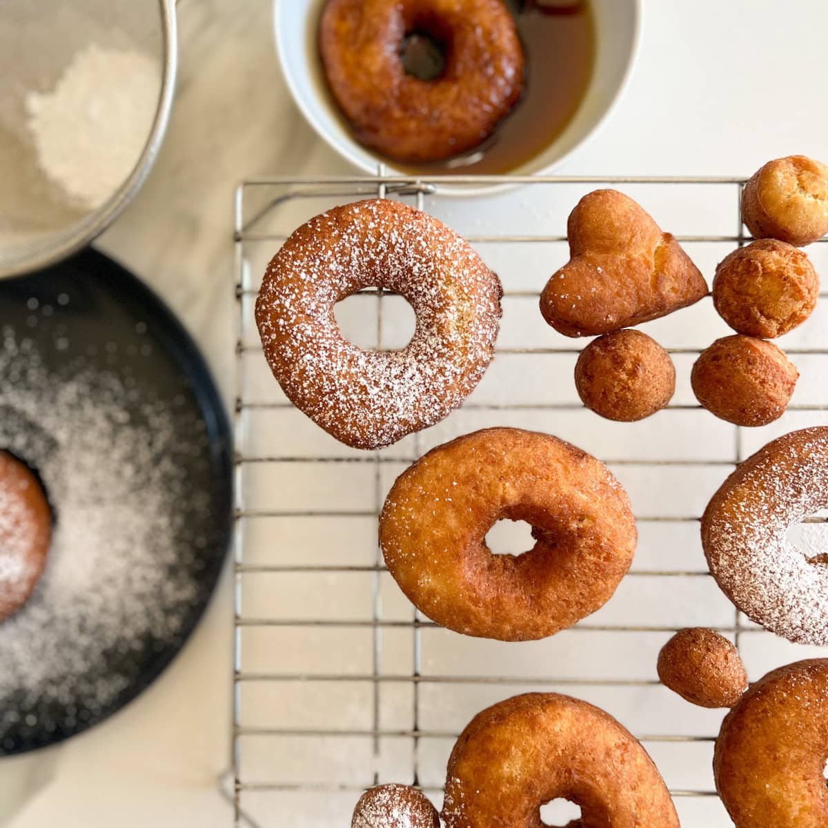 beignes aux patates avec sucre en poudre sur comptoir et grille de pâtisserie