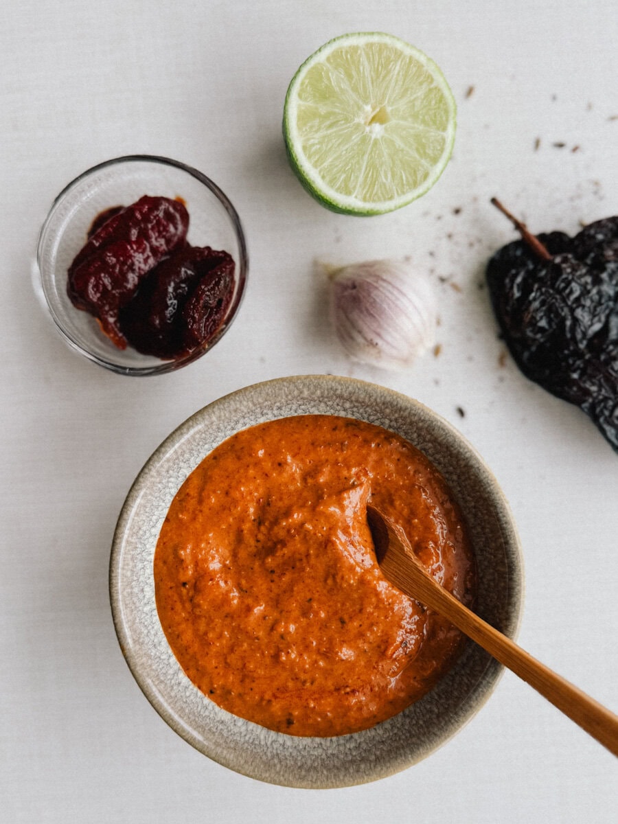 sauce et marinade chipotle dans petit bol sur comptoir avec citron vert, piment ancho, gousse d'ail et piment chipotle