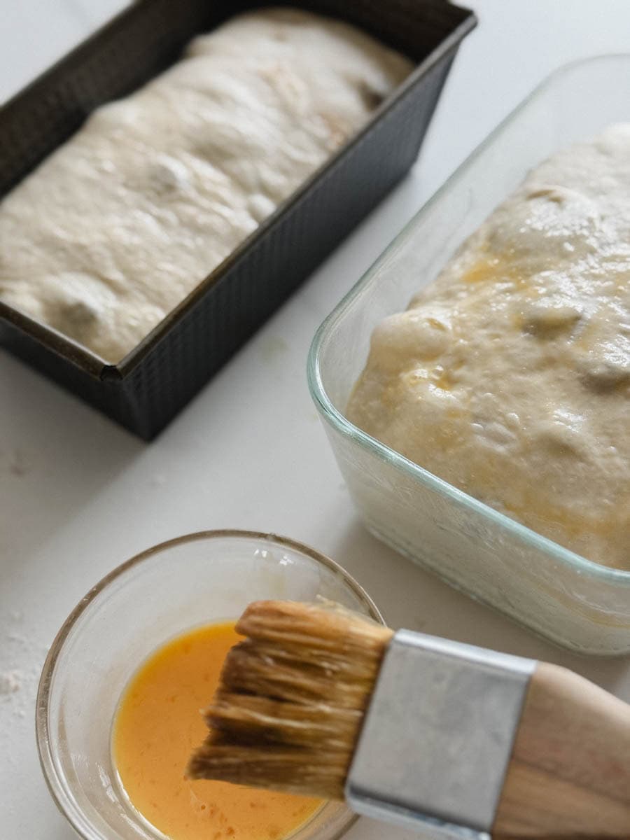 oeuf et dorure avec pinceau à pâtisserie devant 2 pains aux raisons - un sans et un avec dorure liquide