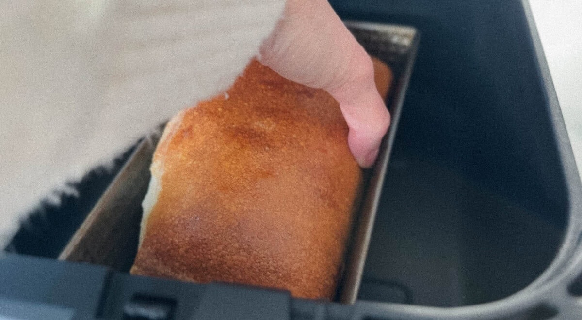 main qui retourne le pain dans le moule dans le panier du air fryer